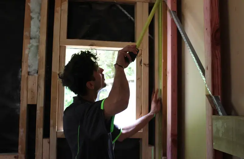 Builder measuring timber wall framing on site — MJones Building